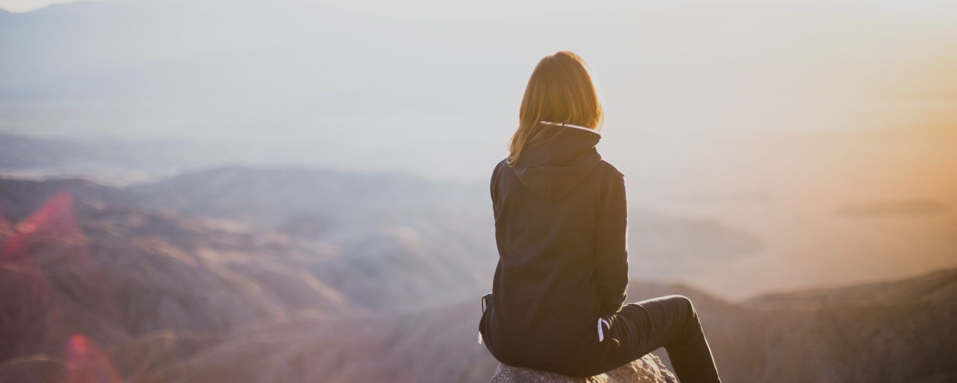 Eine Frau hat einen Berg bewandert - sie reflektiert über die eigene psychische Gesundheit